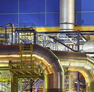 Large silver pipes of an incinerator plant at night. An incinerator plant at a canal with night blue sky.